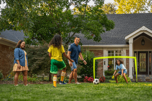 Family playing soccer outside in their yard. 